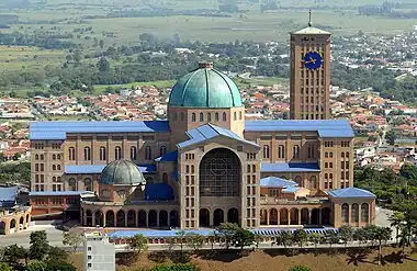 Image 17Basilica of the National Shrine of Our Lady of AparecidaPhotograph: Valter Campanato, Agência Brasil.The Basilica of the National Shrine of Our Lady of Aparecida is a Catholic basilica located in the Brazilian city of Aparecida. According to local tradition, a group of fishermen caught a statue of the Virgin Mary in their nets in 1717, a find which considerably improved their subsequent catches. One of the fishermen kept the statue at his home, which became a popular site for pilgrims. A small chapel was built to house it, but was replaced by successively larger churches as the statue's popularity grew. The present building was built from 1955, and houses 45,000 people.More selected pictures