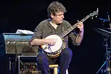 A man sat down playing banjo.