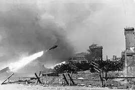 A 28/32&nbsp;cm rocket in flight during the Warsaw Uprising, with piles of spent cases on the right