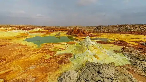 Image 4DallolPhotograph credit: Alexander SavinDallol is a cinder-cone volcano in the Danakil Depression, northeast of the Erta Ale Range in Ethiopia. The area lies up to 120 m (390 ft) below sea level, and has been repeatedly flooded in the past when waters from the Red Sea have inundated it. The Danakil Depression is one of the hottest places on Earth, and the evaporation of seawater after these flooding episodes produced thick deposits of salt, as seen in this landscape. The deposits at Dallol include significant quantities of the carbonate, sulfate and chloride salts of sodium, potassium, calcium and magnesium. Hot springs discharge brine to form the blueish ponds, and small, temporary geysers produce cones of salt.More selected pictures