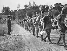 Disarmed Japanese troops marching towards a prisoner of war compound in Api after surrendering to the Australians on 8&nbsp;October 1945