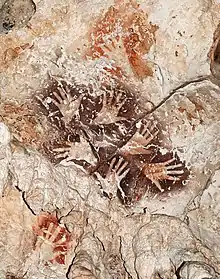 Le « Bouquet de mains », une manifestation remarquable de l’art rupestre de Bornéo, met en scène six mains dans une ronde graphique éternelle. A noter des mains de couleur rouge orangé plus anciennes recouvertes par le motif.