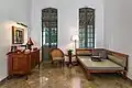 Lobby  lounge of Amantaka Suite with armchair and couch, wooden furniture and coffee machine.