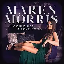 An image of a long brown-haired woman in a green dress sitting on a purple loveseat.