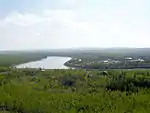 A wide river winds through a forest and by a town.