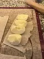 peeled, quartered apples lying on a piece of pastry crust