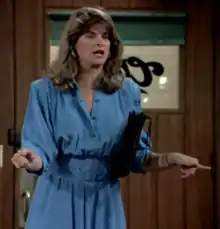 A brunette woman in a blue dress using both of her index fingers to point toward her view and wide away from each other.