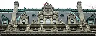 Photograph showing the elaborate details of the mansard roof, with carved statues in front