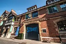 Image of the The Story Museum building frontage incluidng the main double gates, which feature The Story Museum logo