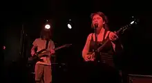 The group Wednesday performing in Grand Rapids, Michigan. Hartzman is singing, and Baechtold is playing bass guitar.